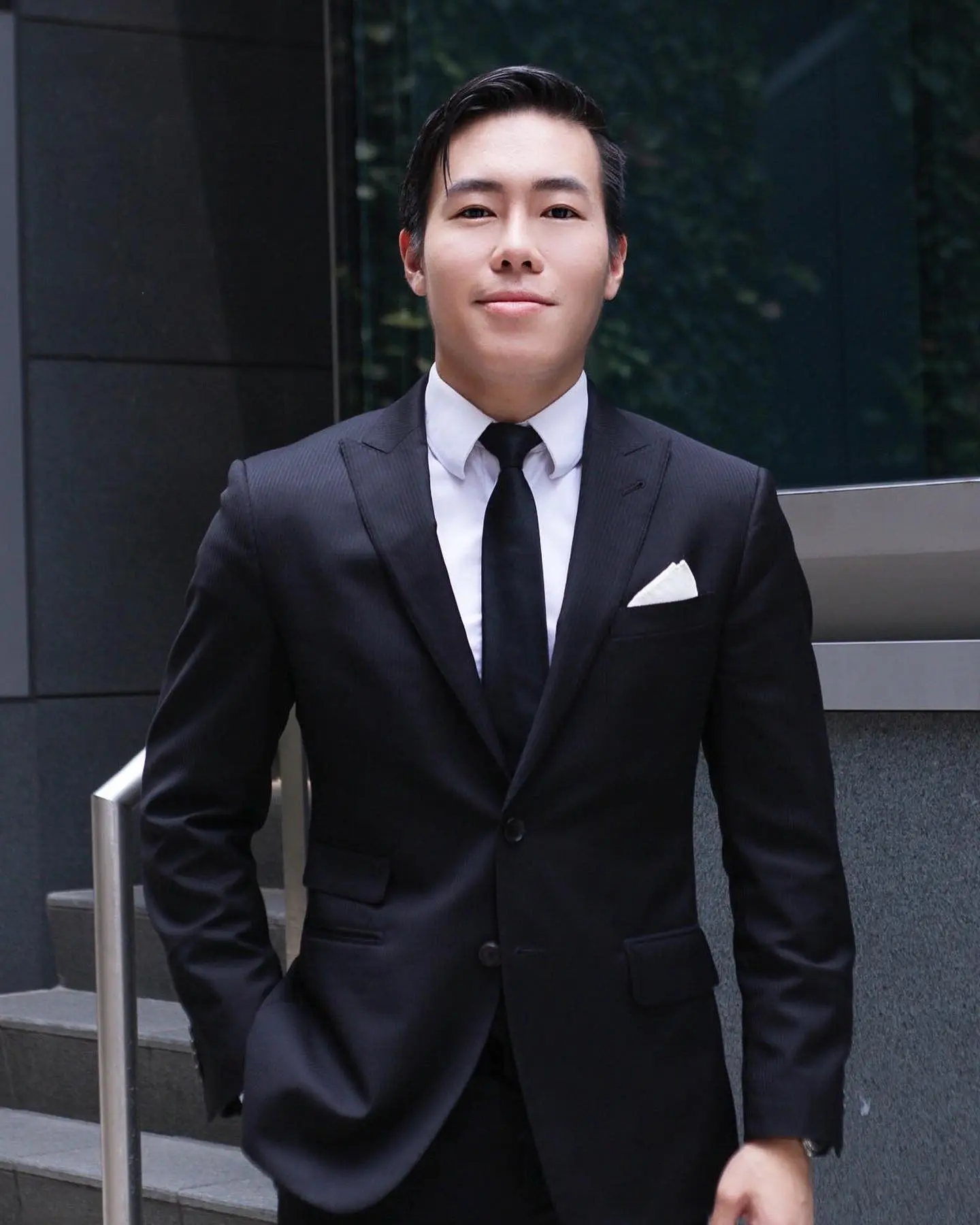 Luke Lee in a dark suit outside an office building